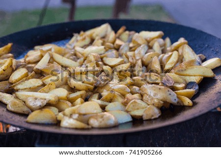 the potato is fried in a frying pan on the street during a picnic with friends. cooking french fries.
