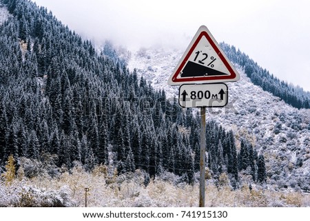 Winter road in the mountains and a road sign.