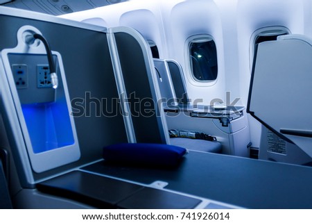 Cup of fresh coffee and newspaper on table in airplane interior