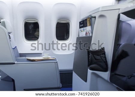 Cup of fresh coffee and newspaper on table in airplane interior