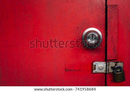 Old red wooden door texture background with door knob and rusty padlock. Copy space.