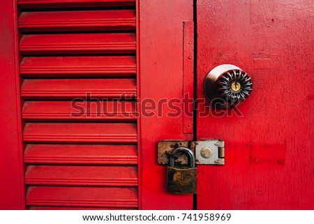 Old red wooden door texture background with door knob and rusty padlock. Copy space.