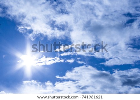 The sun in the sky with white clouds. The sun shines through white clouds.