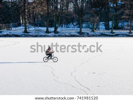 
The teenager rides a bicycle on thin  ice. 
Life threatening.