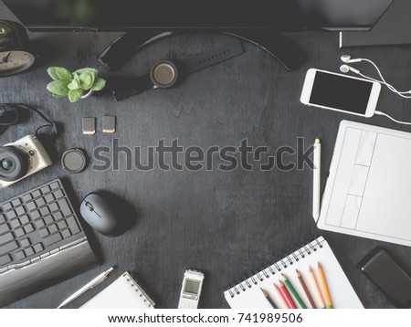 top view of graphic designer table with graphic tablet, smartphone, mouse, keyboard on black wooden background with copy space, creative designs concept.
