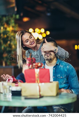 Young woman gives a gift to a young man in the cafe