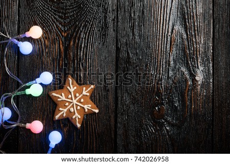 Christmas gingerbread cookie and colorful garland on wooden background