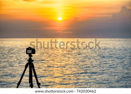 Dslr digital professional camera stand on tripod photographing sea, twilight sky and cloud landscape. 