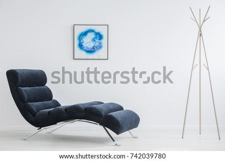 Creative blue poster hanging on the wall in white room with metal hanger and dark couch