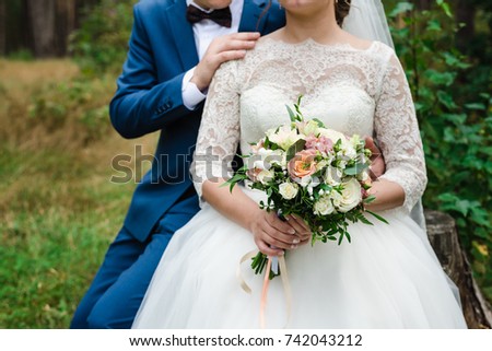 the bride is holding a bouquet, the bride's bouquet, the bridegroom embraces the bride, groom with the bride