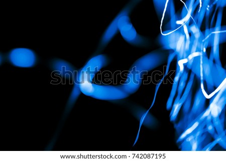 Abstract xmas blue transparent sparkles or glitter lights. Christmas festive black background. Defocused lines bokeh or particles. Template for design