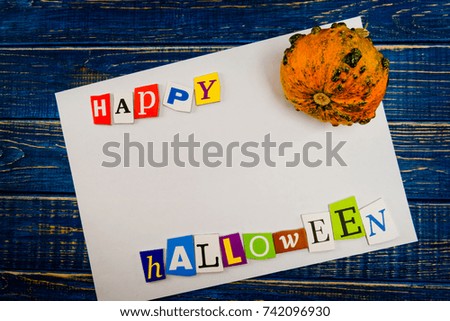 Inscription "Happy Halloween" with empty copy space and pumpkin on wooden blue table. Halloween Background.