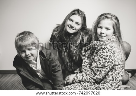 Portrait of adorable beautiful young family looking lovely in winter style clothing over light background. Healthy, emotional, peaceful joyful happiness lifestyle