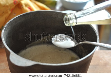 Process of quenching the baking soda with the vinegar in a spoon over a cast-iron bowl with the batter. Close-up picture. Process of cooking.