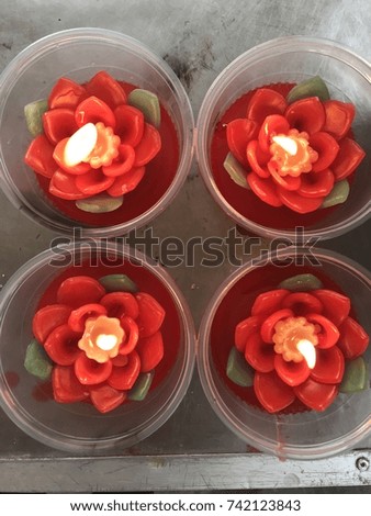 Close-up of 4 flower shape candles lighting in the plastic cup