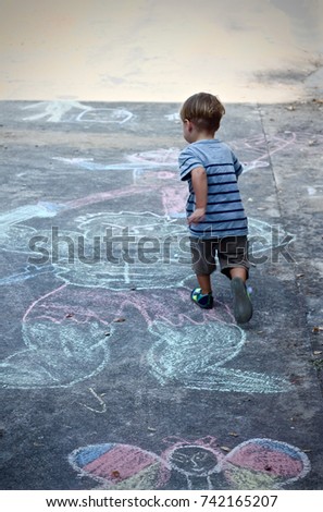 Boy Running Away in a Playground Covered in Chalk Cartoon Drawings