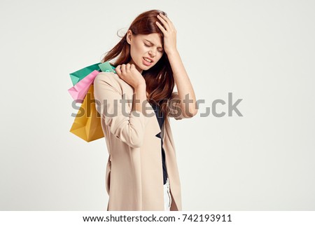 woman holds on to her head, in her hand bags on a light background, shopping                               