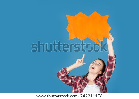 teen girl pointing at blank speech bubble isolated on blue