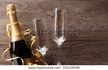 Photo of two wineglasses, bottle of champagne, gold ribbons