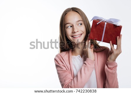 Cute teenage girl peeking at gift box