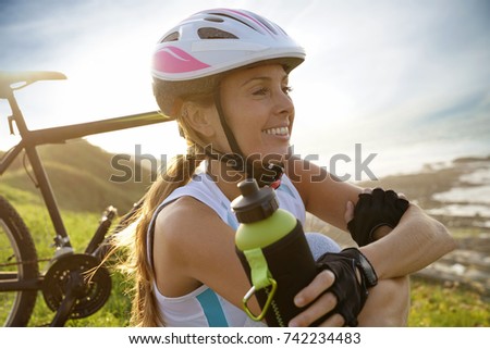 Portrait of woman on biking journey drinking water from bottle
