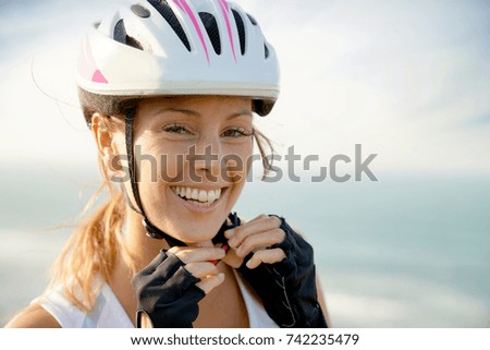 Portrait of smiling woman on bike ride putting helmet on