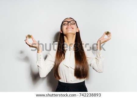 young modern successful business woman wearing glasses keeps golden bitcoins and looks happy