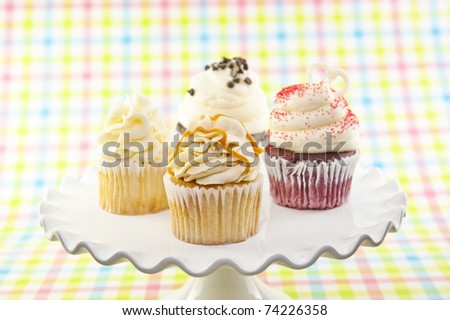 A variety of assorted cupcakes on a plate with selective focus on front cupcake