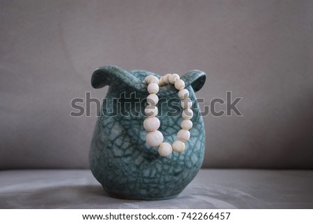 LJUBLJANA, SLOVENIA - 1. SEPTEMBER: A picture of a white pearl necklace on the aesthetic artistic vase, with the dark cream color in the background.