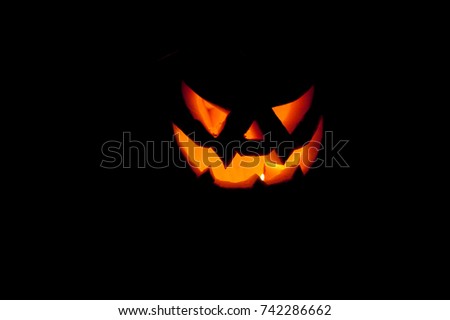 a terrifying halloween pumpkin illuminates the darkness around it