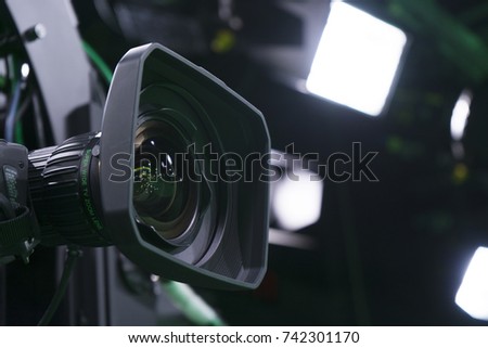 Broadcast studio camera in green studio room with LED lights on the ceiling.