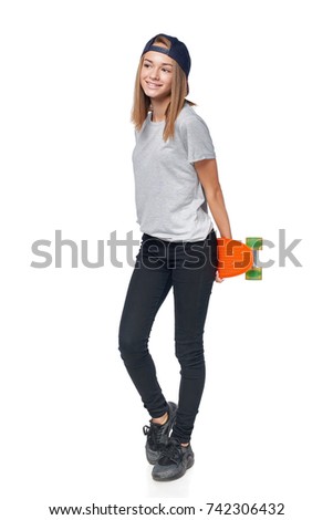 Happy teen girl in full length holding skate board looking to the side at blank copy space, isolated on white background