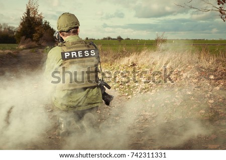 Photographer in field and smoke of battle