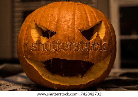 A scary, unlit, pumpkin jack-o-lantern sits on a table after being carved