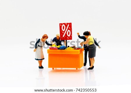 Miniature people: Shoppers buy goods on sale with discount tray.
