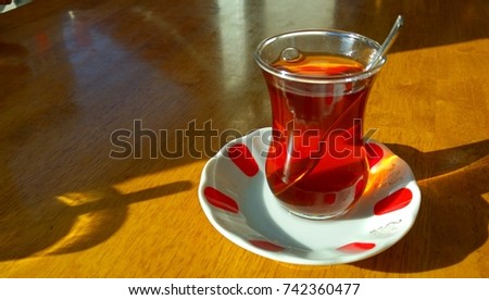 A typical Turkish "armudu" tea glass on a saucer. It is also popular in Azerbaijan. Turkish thin waist tea glass stock image.