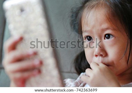 Close-up little girl looking mobile phone on the sofa
