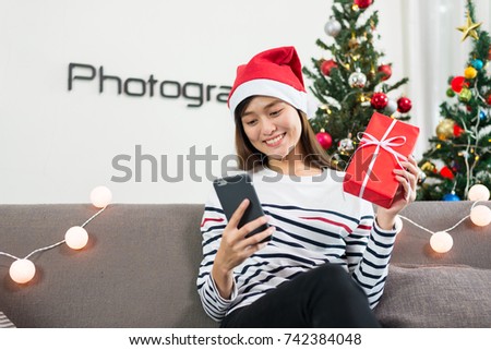 Young asian women holding gift boxes and use smartphones, Christmas.