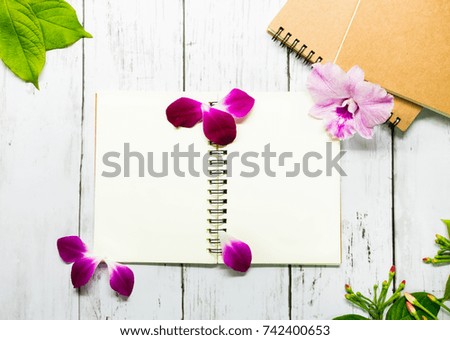 The book is placed in the center of the white wood adorned with purple orchids to enhance the vividness of the picture.