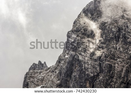 Detail of a mountain rock face, background or wallpaper picture of big wall rock climb, clouds and mist, stone and rock surface.