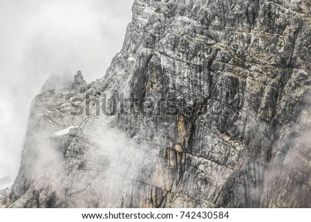 Detail of a mountain rock face, background or wallpaper picture of big wall rock climb, clouds and mist, stone and rock surface.