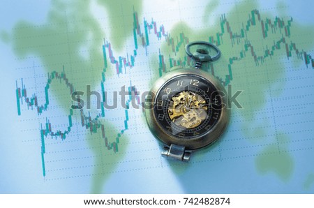 Candlestick chart graphic and pocket watch in light