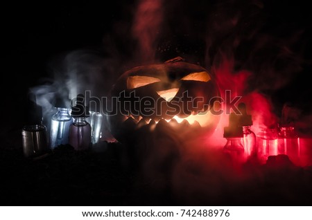 Colorful vape liquids with Halloween pumkin on dark background. Vape Halloween party or vape promo concept on Halloween holidays promo