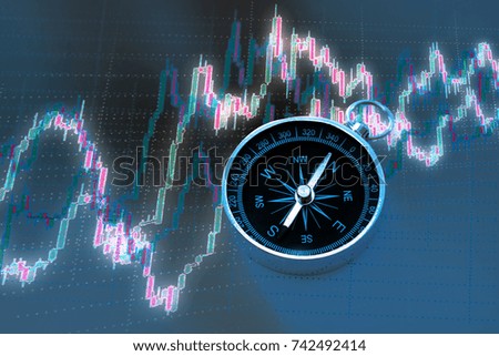 Candlestick chart graphic and black compass in light