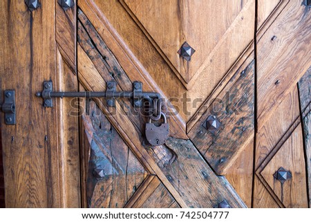 An old padlock at the antique wooden door