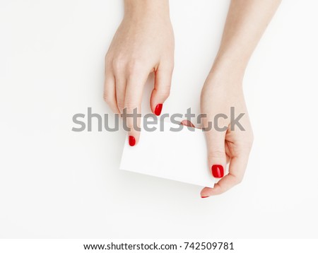 Flat lay, top view. Beauty and fashion concept. Beautiful female hands with red manicure. Minimal style. Minimalist photography. Pale composition with girl's hand holding card on white background Royalty-Free Stock Photo #742509781