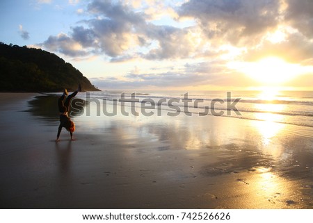 Handstand person on beach at sunrise