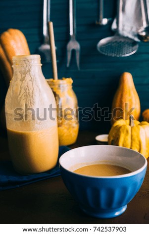 Pumpkin and potato  soup on a jar  glass container in a rustic setup with green background
