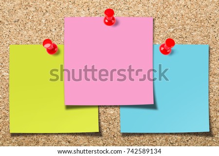 Cork board with three colorful blank sticky notes.
