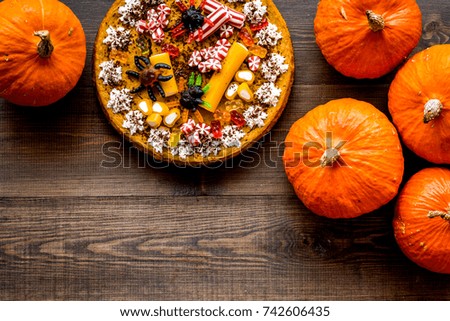 Homemade pie for halloween decorated gummy spiders among pumpkins on wooden background top view copyspace